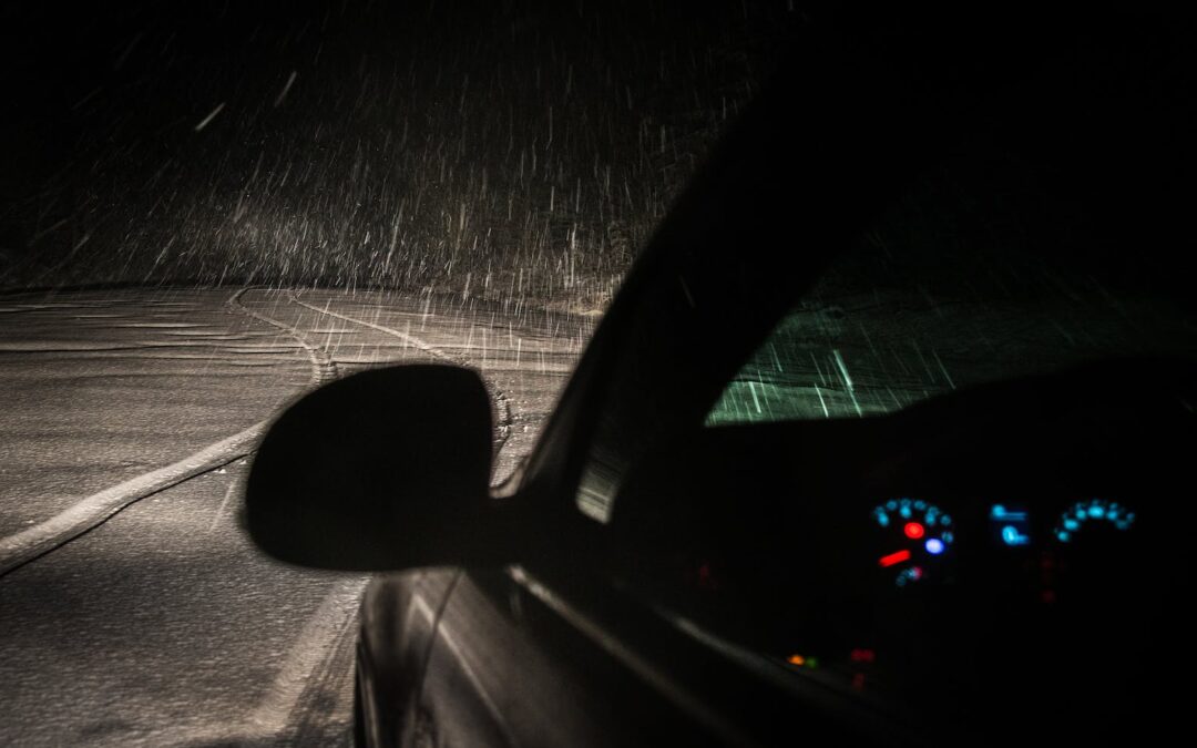 black car on roadway while raining during nighttime